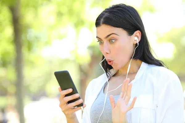 Surprised woman finding music content on phone — Stock Photo, Image