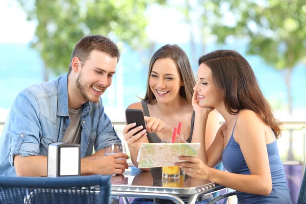 Grupo de turistas comprobando teléfono y mapa de vacaciones — Foto de Stock