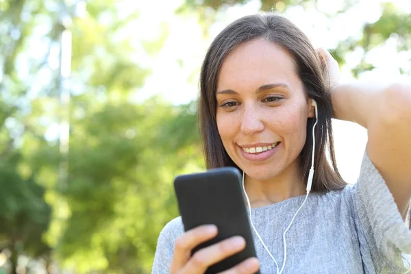 Mulher adulta ouvindo música verificando telefone inteligente — Fotografia de Stock