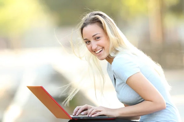 Menina adolescente feliz olha para você usando um laptop — Fotografia de Stock