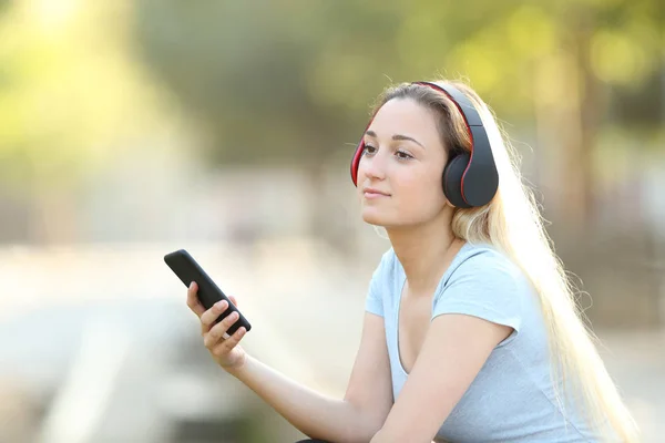 Relaxed girl listening to music with headphones and phone — Stock Photo, Image