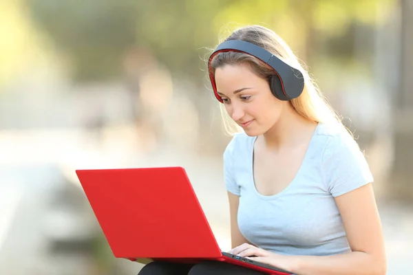 Allvarlig tonårs flicka med hjälp av laptop och hörlurar — Stockfoto