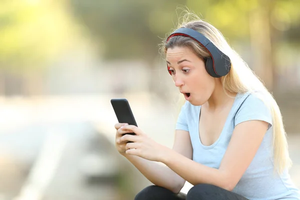 Förvånad tonårs flicka hitta musik erbjudanden på telefon — Stockfoto