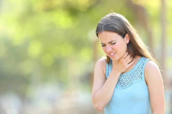 Женщина, страдающая от боли в горле в парке — стоковое фото