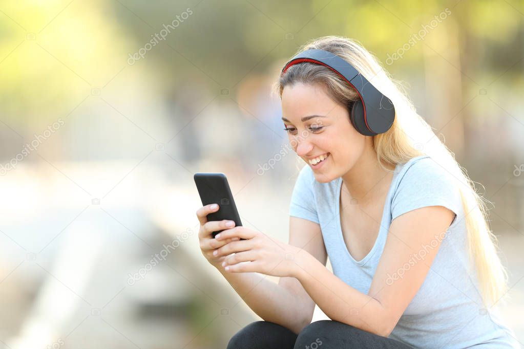 Happy teenage girl using smart phone in a park