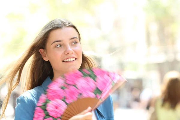 Mujer feliz usando un ventilador caminando en la calle en verano —  Fotos de Stock