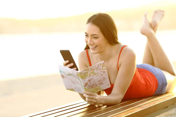 Feliz turista verificando telefone e guia na praia — Fotografia de Stock