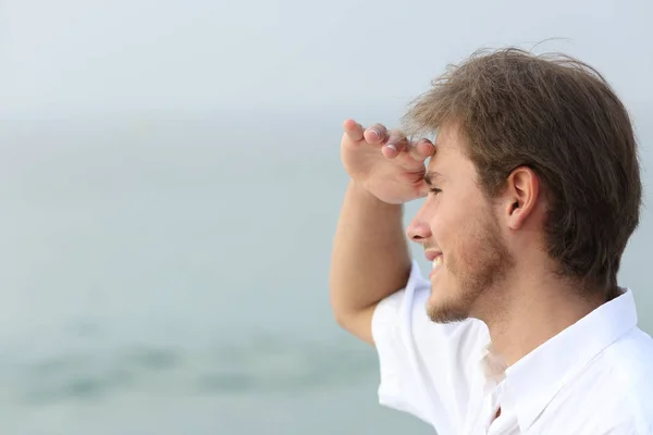 Homme heureux scoutisme sur la plage avec la main sur le front — Photo