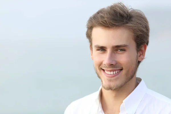 Porträt eines glücklichen Mannes, der am Strand in die Kamera blickt — Stockfoto