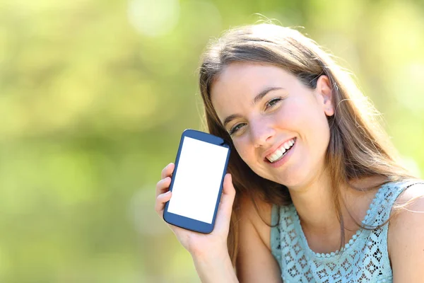 Femme heureuse montrant un écran de téléphone vide sur vert — Photo