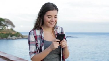 Mutlu genç kız sahilde akıllı telefon kullanarak yürüyüş