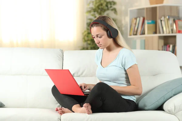Súlyos lány használ egy laptop és fejhallgató-ra egy dívány — Stock Fotó