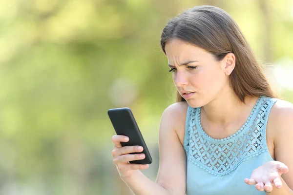 Femme confus vérifier téléphone intelligent sur vert — Photo