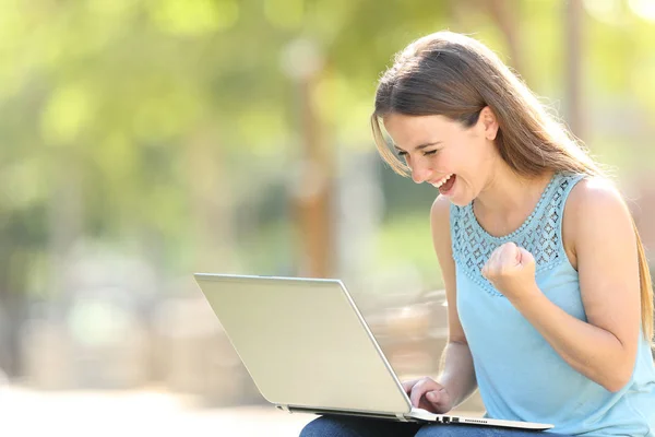 Excited woman checking laptop celebrating good news