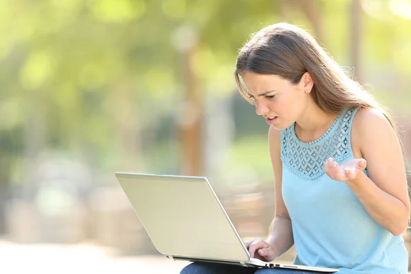 Femme confondue utilisant un ordinateur portable dans un parc — Photo