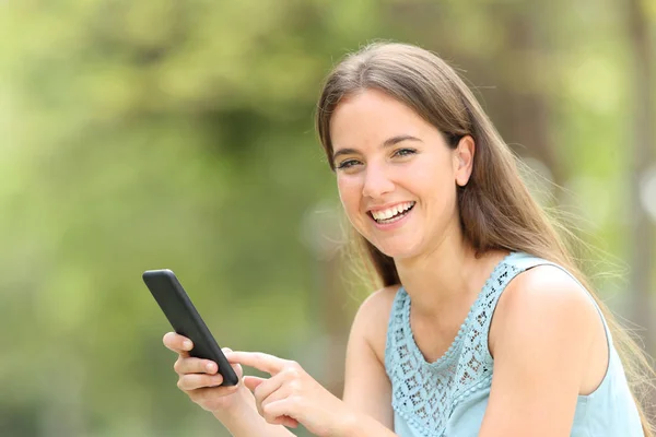 Zabawna kobieta trzyma inteligentny telefon patrząc na Ciebie na zielono — Zdjęcie stockowe
