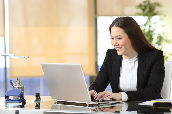 Heureuse femme d'affaires écrivant sur ordinateur portable au bureau — Photo