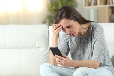 Evde endişeli kadın akıllı telefon kontrol