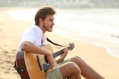 Adam sahilde oturup gitar çalmak