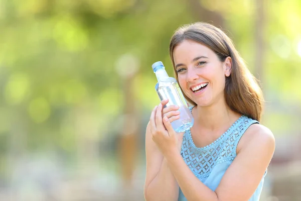 Mujer mostrando una botella de agua de plástico en verde — Foto de Stock