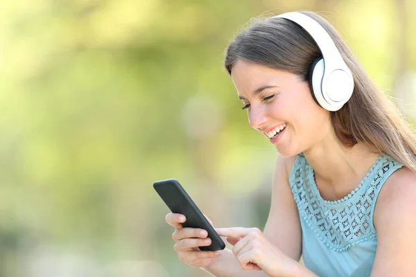 Mulher feliz está ouvindo música usando telefone inteligente — Fotografia de Stock