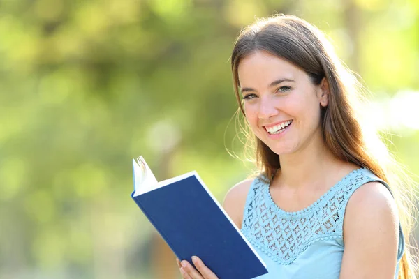 Gelukkige vrouw kijkt naar de camera die een boek vasthoudt — Stockfoto