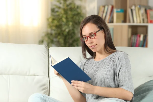 Ernsthafte Frau mit Brille zu Hause beim Lesen eines Buches — Stockfoto