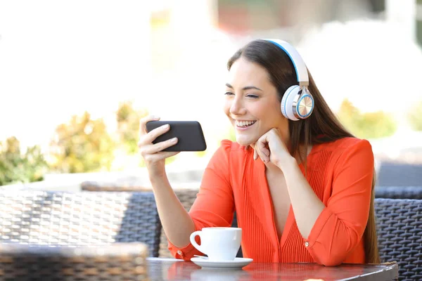 Lycklig kvinna tittar på media på smart telefon i en restaurang — Stockfoto
