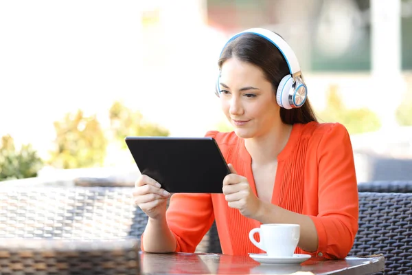 Woman watching and listening media on a tablet in a bar — Stock Photo, Image