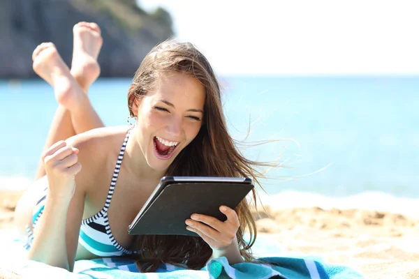 Opgewonden meisje in bikini controleren tablet op het strand — Stockfoto