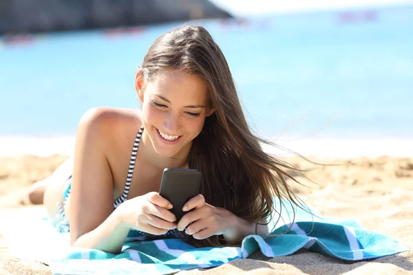 Gelukkig meisje in bikini met behulp van slimme telefoon op het strand — Stockfoto