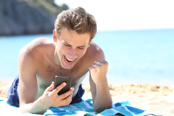 Волнующий мальчик проверяет телефон на пляже — стоковое фото