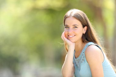 Mutlu kadın yeşil bir parkta kameraya bakıyor