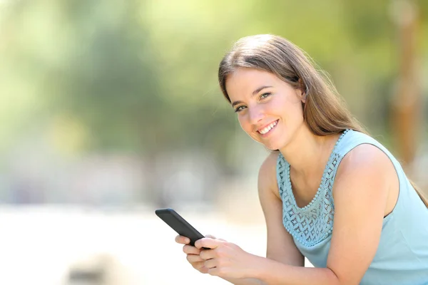 Mujer feliz sosteniendo smartphone mira a la cámara — Foto de Stock