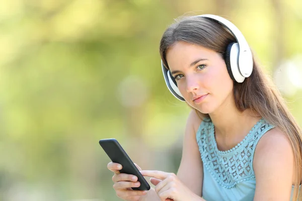 Alvorlig kvinde lytter til musik holder smart telefon - Stock-foto