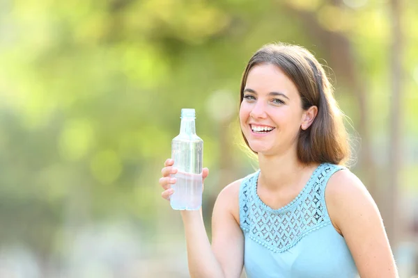 Счастливая женщина держит бутылку воды на зеленом фоне — стоковое фото