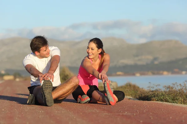 Пара бегунов растягивают ноги после занятий спортом — стоковое фото