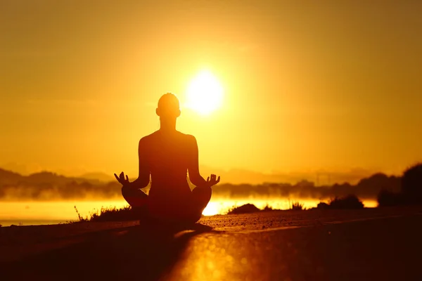 Silueta de mujer practicando ejercicio de yoga al amanecer — Foto de Stock