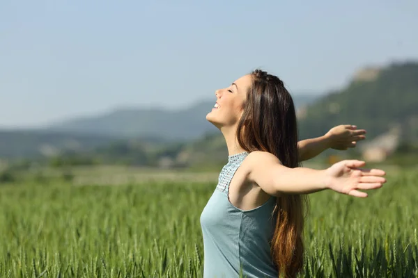 Mujer feliz respirando profundamente aire fresco en un campo —  Fotos de Stock