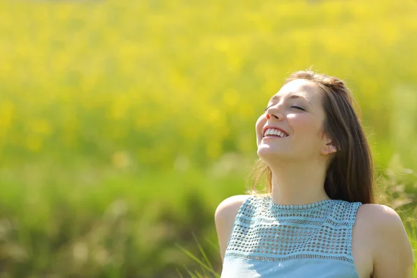 Счастливая женщина отдыхает дыша свежим воздухом в поле — стоковое фото