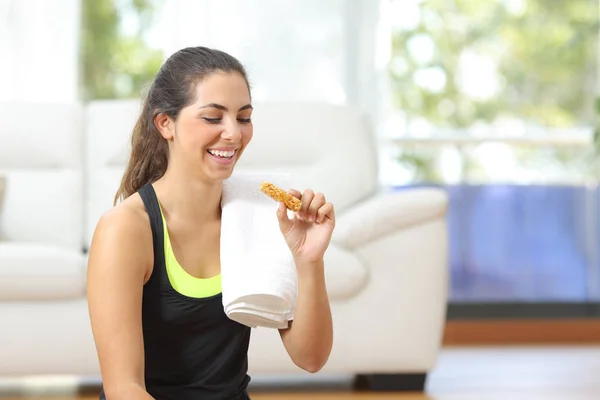 Женщина ест энергетический бар после занятий спортом дома — стоковое фото