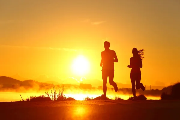 Par shilouette körs vid soluppgången på stranden — Stockfoto
