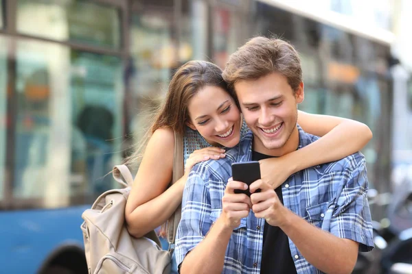 Casal usando telefone com um ônibus no fundo — Fotografia de Stock