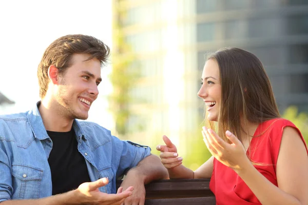 Щаслива пара розмовляє сидячи на лавці на вулиці — стокове фото