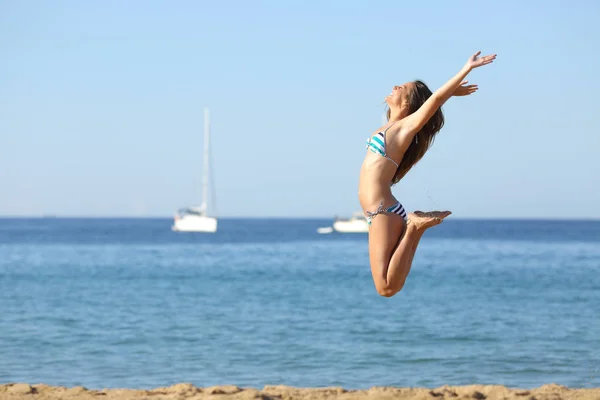 Aufgeregte Frau im Bikini springt am Strand — Stockfoto