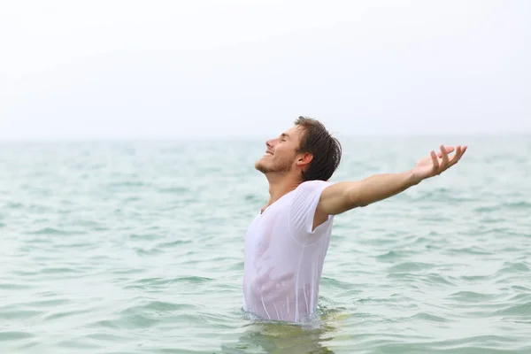 Счастливый мужчина вытянулся, купаясь на пляже — стоковое фото