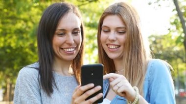 Mutlu yetişkin kadın ve genç kız bir parkta akıllı telefon kontrol