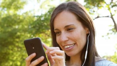 Romantik yetişkin kadın bir parkta akıllı telefonda müzik dinlerken