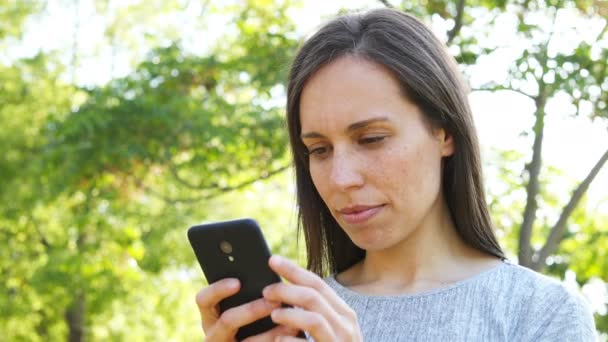 Vzrušená Dospělá Žena Kontroluje Elegantní Telefon Stojící Parku — Stock video