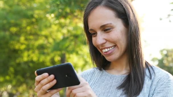 快乐的成年女人在公园的水平位置观看智能手机的视频 — 图库视频影像